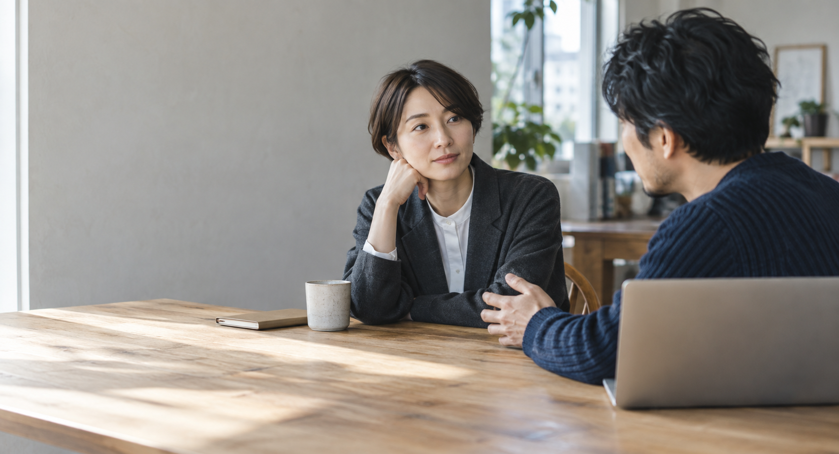 窓から自然光が入る仕事場で、相手の話をじっくり聞く二人。生成した利用場面のイメージです。